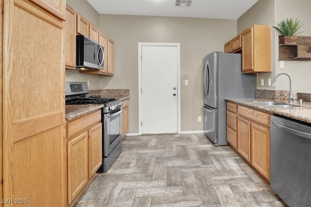 6581 Netherseal Ave, Las Vegas, NV 89139 - kitchen featuring appliances with stainless steel finishes, a sink, light brown cabinets, and light stone countertops