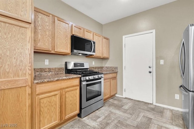 6581 Netherseal Ave, Las Vegas, NV 89139 - kitchen featuring appliances with stainless steel finishes, light brown cabinetry, light stone counters, and baseboards