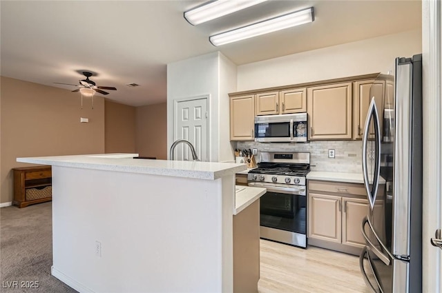 9303 Gilcrease Ave Unit 1002, Las Vegas, NV 89149 - kitchen featuring appliances with stainless steel finishes, a kitchen island with sink, light countertops, tasteful backsplash, and a ceiling fan