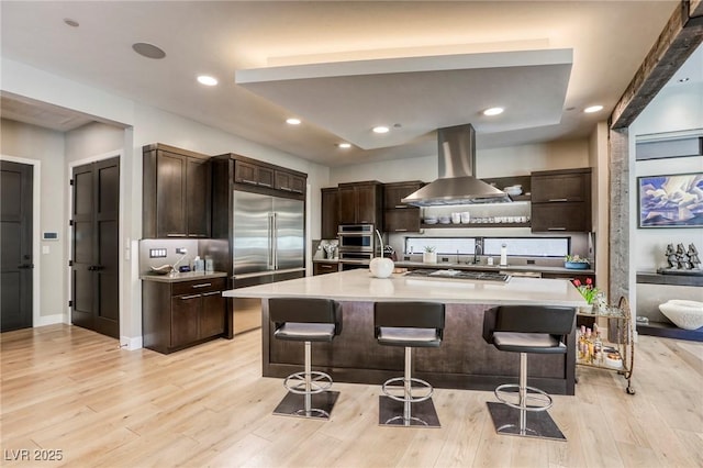 787 Keyland St, Las Vegas, NV 89138 - kitchen with island range hood, appliances with stainless steel finishes, a breakfast bar area, light wood-style floors, and recessed lighting
