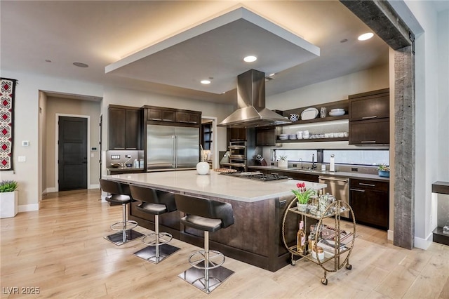787 Keyland St, Las Vegas, NV 89138 - kitchen with island exhaust hood, appliances with stainless steel finishes, dark brown cabinetry, a kitchen bar, and light countertops