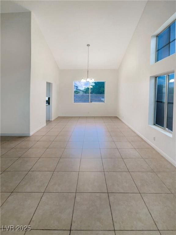 6120 Desert Haven Rd, Las Vegas, NV 89130 - empty room with high vaulted ceiling, a chandelier, light tile patterned floors, and baseboards