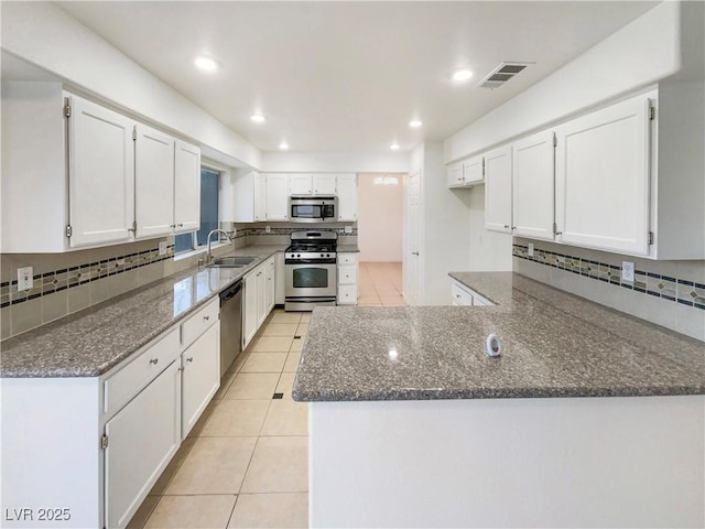 6120 Desert Haven Rd, Las Vegas, NV 89130 - kitchen with appliances with stainless steel finishes, a sink, dark stone counters, a peninsula, and backsplash