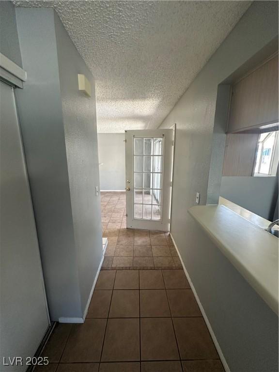 227 N Lamb Blvd Unit A, Las Vegas, NV 89110 - corridor featuring a textured ceiling, dark tile patterned floors, and baseboards