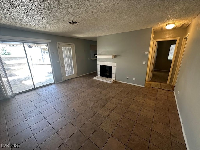 227 N Lamb Blvd Unit A, Las Vegas, NV 89110 - unfurnished living room featuring a fireplace, plenty of natural light, baseboards, dark tile patterned flooring, and a textured ceiling