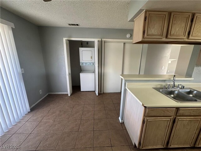 227 N Lamb Blvd Unit A, Las Vegas, NV 89110 - kitchen with stacked washer / dryer, a sink, tile patterned floors, light countertops, and a textured ceiling
