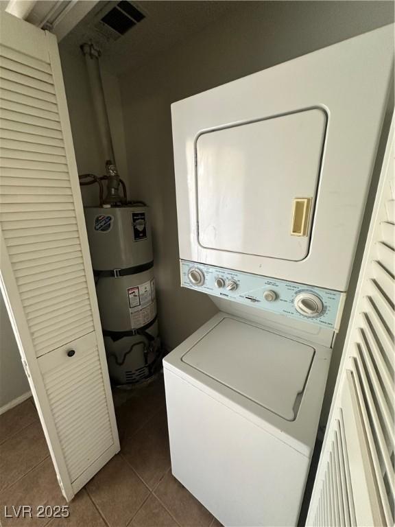 227 N Lamb Blvd Unit A, Las Vegas, NV 89110 - washroom featuring stacked washer / dryer, strapped water heater, and dark tile patterned floors