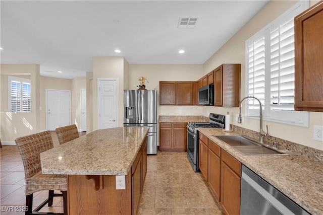 1104 Aspen Cliff Dr, Henderson, NV 89011 - kitchen featuring stainless steel appliances, a kitchen breakfast bar, a sink, a center island, and brown cabinets