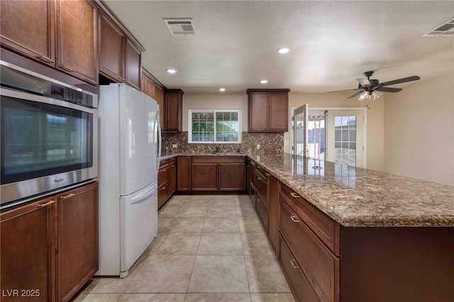 616 Fernbrook Dr, Henderson, NV 89002 - kitchen with freestanding refrigerator, a peninsula, decorative backsplash, oven, and dark stone countertops