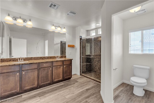 5661 Brimstone Hill Ave, Las Vegas, NV 89141 - bathroom featuring wood finished floors, a stall shower, toilet, double vanity, and baseboards