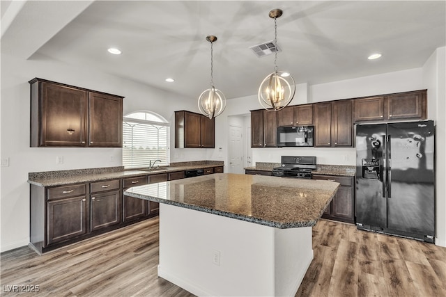 5661 Brimstone Hill Ave, Las Vegas, NV 89141 - kitchen featuring black appliances, a chandelier, dark brown cabinetry, a center island, and dark stone countertops