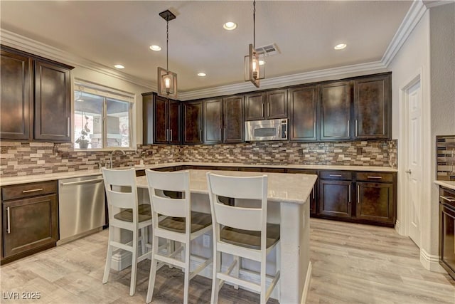 5635 Mesa Mountain Dr, Las Vegas, NV 89135 - kitchen with appliances with stainless steel finishes, crown molding, decorative backsplash, dark brown cabinetry, and light wood finished floors