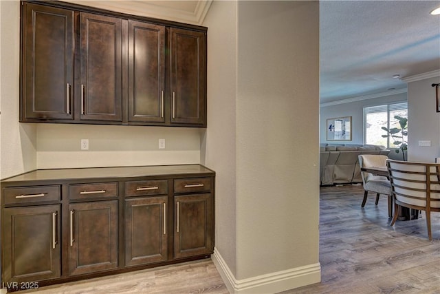 5635 Mesa Mountain Dr, Las Vegas, NV 89135 - kitchen featuring crown molding, light wood-type flooring, dark brown cabinets, open floor plan, and baseboards
