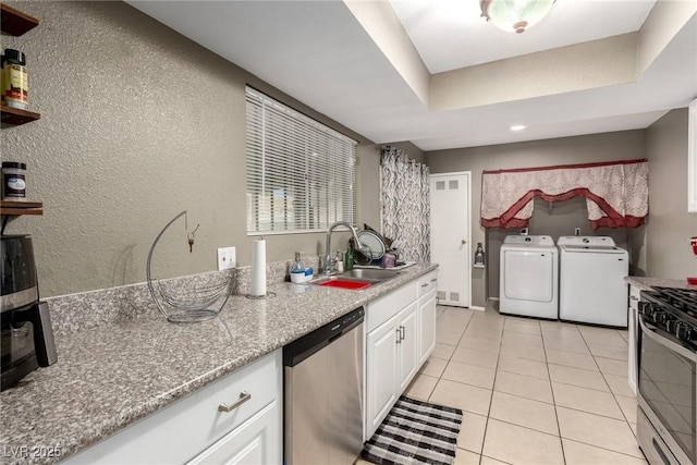 4213 Essex Green Ct, Las Vegas, NV 89110 - kitchen with appliances with stainless steel finishes, a sink, washer and dryer, white cabinetry, and light tile patterned floors