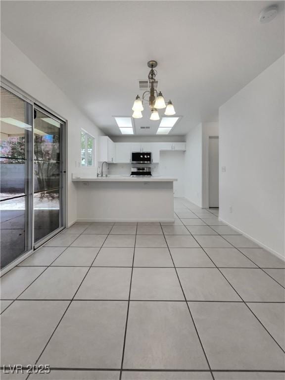 7900 Wood Shadow Ct, Las Vegas, NV 89131 - kitchen with light countertops, white cabinets, a peninsula, and stainless steel microwave