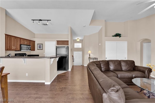 5000 Red Rock St Unit 259, Las Vegas, NV 89118 - living room featuring wood finished floors, arched walkways, rail lighting, a ceiling fan, and lofted ceiling