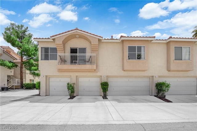 5000 Red Rock St Unit 259, Las Vegas, NV 89118 - view of front of home with a garage, stucco siding, driveway, a tiled roof, and a balcony