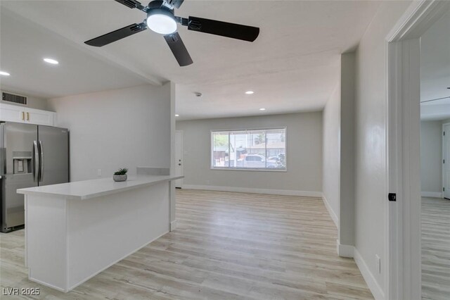 1825 Howard Ave, Las Vegas, NV 89104 - kitchen featuring stainless steel fridge with ice dispenser, light countertops, ceiling fan, light wood-type flooring, and white cabinets