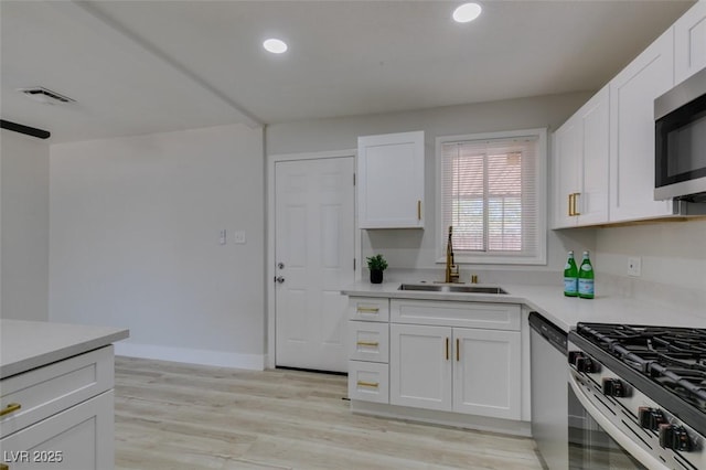 1825 Howard Ave, Las Vegas, NV 89104 - kitchen featuring a sink, appliances with stainless steel finishes, white cabinets, light countertops, and light wood-style floors