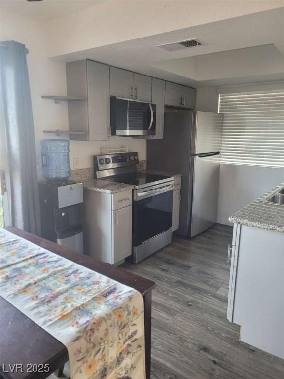 5335 Rod Ct Unit 102, Las Vegas, NV 89122 - kitchen with appliances with stainless steel finishes, dark wood-style flooring, gray cabinetry, and open shelves
