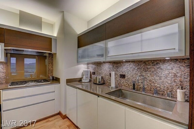 3750 S Las Vegas Blvd Unit 3111, Las Vegas, NV 89158 - kitchen featuring stainless steel gas stovetop, backsplash, white cabinets, a sink, and light wood-style floors