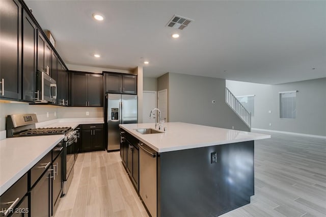 9239 Albus Hills Ave, Las Vegas, NV 89143 - kitchen featuring stainless steel appliances, a sink, light wood finished floors, open floor plan, and a kitchen island with sink