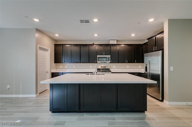 9239 Albus Hills Ave, Las Vegas, NV 89143 - kitchen featuring stainless steel appliances, a sink, baseboards, light countertops, and a kitchen island with sink