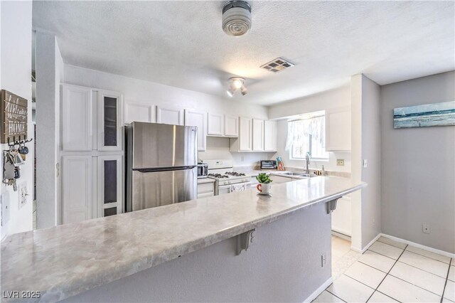 844 Balzar Ave, Las Vegas, NV 89106 - kitchen with freestanding refrigerator, white gas range oven, a sink, white cabinets, and light countertops