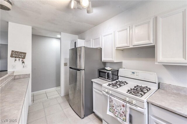 844 Balzar Ave, Las Vegas, NV 89106 - kitchen with appliances with stainless steel finishes, white cabinetry, light countertops, light tile patterned floors, and baseboards