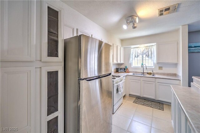 844 Balzar Ave, Las Vegas, NV 89106 - kitchen with freestanding refrigerator, white gas stove, a sink, light countertops, and white cabinets
