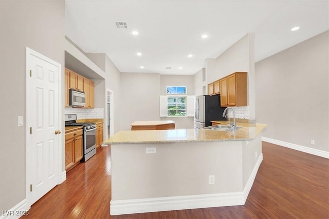 1212 E Rome Blvd, North Las Vegas, NV 89086 - kitchen featuring appliances with stainless steel finishes, wood finished floors, tasteful backsplash, a sink, and a kitchen island