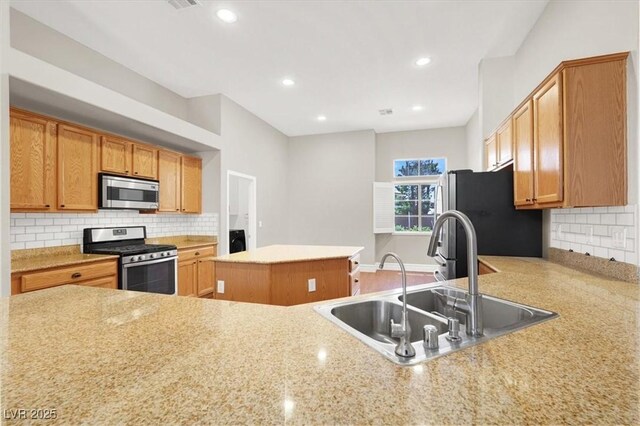 1212 E Rome Blvd, North Las Vegas, NV 89086 - kitchen with stainless steel appliances, a sink, a kitchen island, tasteful backsplash, and recessed lighting