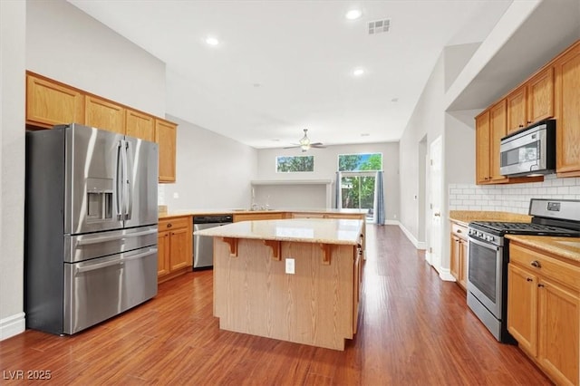 1212 E Rome Blvd, North Las Vegas, NV 89086 - kitchen featuring stainless steel appliances, a peninsula, ceiling fan, wood finished floors, and decorative backsplash