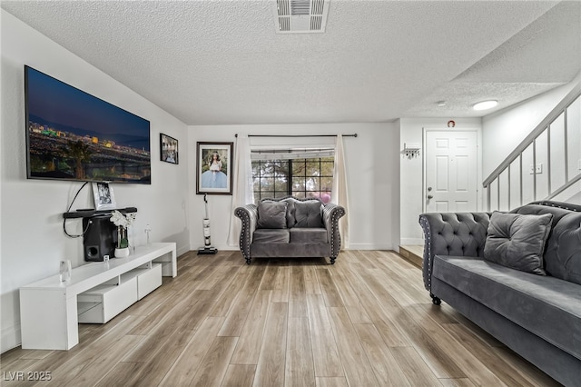 2507 Albemarle Way, Henderson, NV 89014 - living room featuring light wood-type flooring, a textured ceiling, stairs, and baseboards