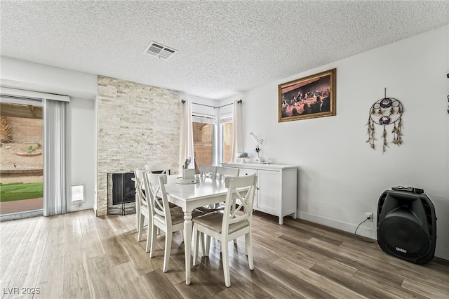 2507 Albemarle Way, Henderson, NV 89014 - dining space with wood finished floors, a stone fireplace, a textured ceiling, and baseboards