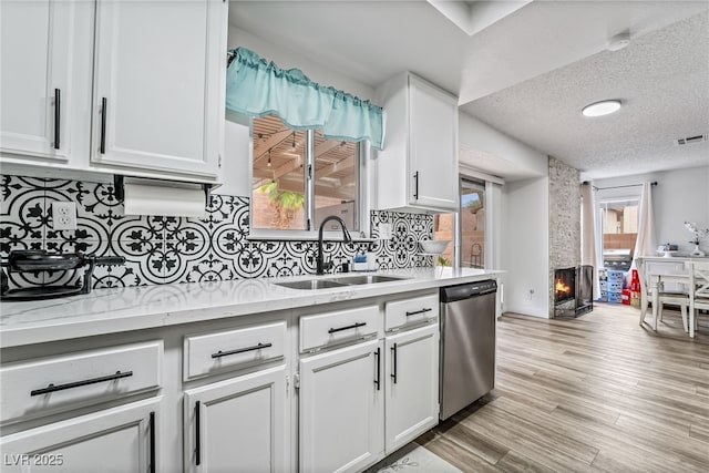 2507 Albemarle Way, Henderson, NV 89014 - kitchen featuring stainless steel dishwasher, a sink, white cabinets, backsplash, and a large fireplace