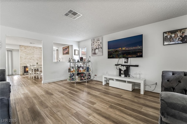 2507 Albemarle Way, Henderson, NV 89014 - living room featuring wood finished floors, a textured ceiling, baseboards, and a stone fireplace