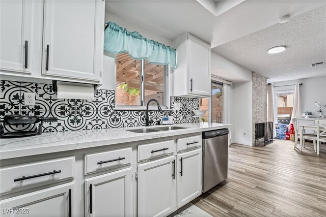 2507 Albemarle Way, Henderson, NV 89014 - kitchen with stainless steel dishwasher, a sink, white cabinets, decorative backsplash, and a textured ceiling