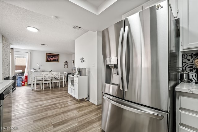 2507 Albemarle Way, Henderson, NV 89014 - kitchen with stainless steel appliances, light countertops, light wood-type flooring, a textured ceiling, and white cabinetry