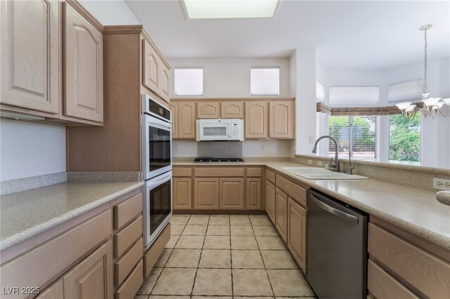 9812 Folsom Dr, Las Vegas, NV 89134 - kitchen featuring stainless steel appliances, light brown cabinetry, a sink, light countertops, and a chandelier