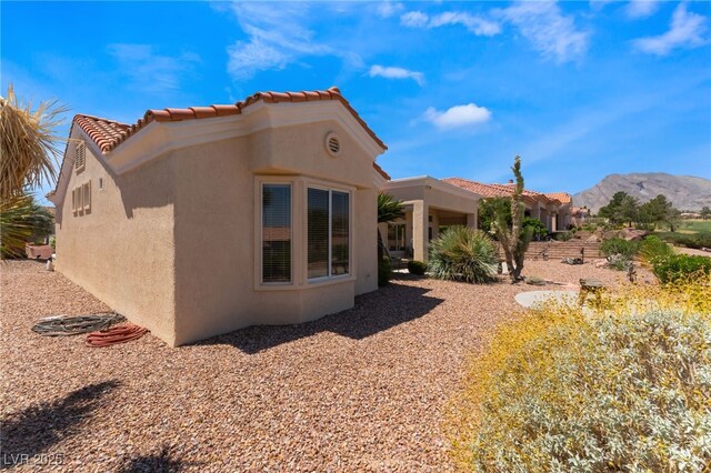 9812 Folsom Dr, Las Vegas, NV 89134 - view of side of property featuring stucco siding, a tile roof, and a mountain view