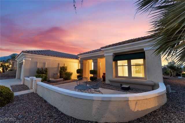 9812 Folsom Dr, Las Vegas, NV 89134 - back of property at dusk with stucco siding, a tile roof, and a garage