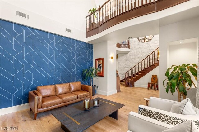10301 Orkiney Dr, Las Vegas, NV 89144 - living room with stairs, light wood-type flooring, a towering ceiling, an accent wall, and baseboards