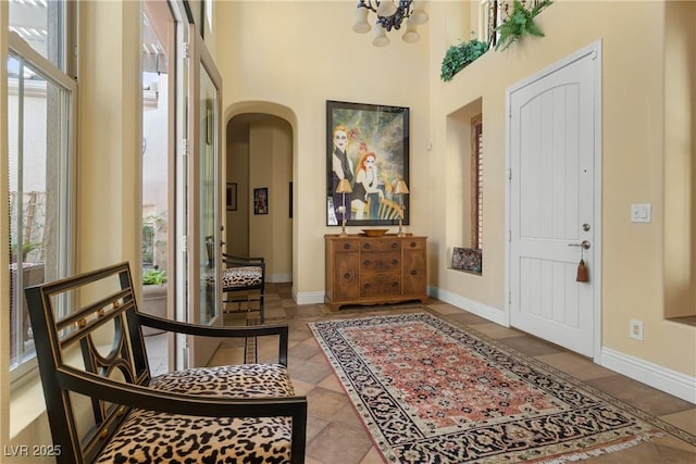 7206 Laramie Ave, Las Vegas, NV 89113 - tiled foyer with arched walkways, a high ceiling, baseboards, and a chandelier