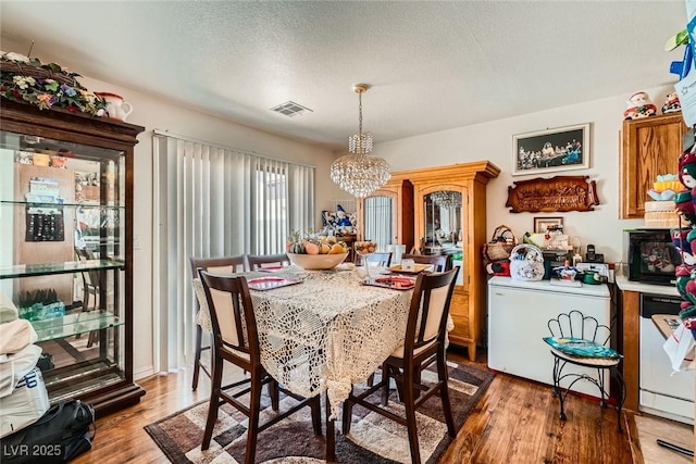 4832 Englewood Ave, Las Vegas, NV 89139 - dining space with a chandelier, light wood-style floors, and a textured ceiling
