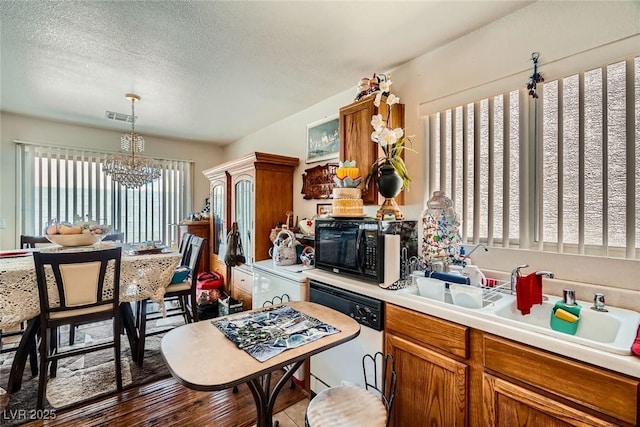 4832 Englewood Ave, Las Vegas, NV 89139 - kitchen with dishwashing machine, black microwave, a chandelier, light countertops, and brown cabinetry