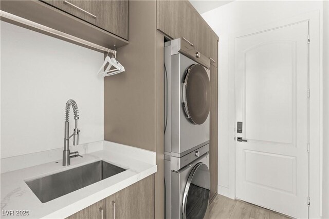 2240 Boutique Ave, Henderson, NV 89044 - laundry area with stacked washer / dryer, cabinet space, and light wood-type flooring