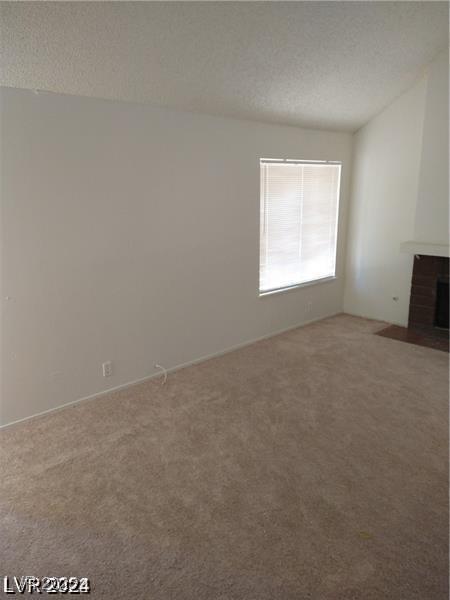 4760 Woodridge Rd, Las Vegas, NV 89121 - unfurnished living room with carpet, a textured ceiling, and a fireplace