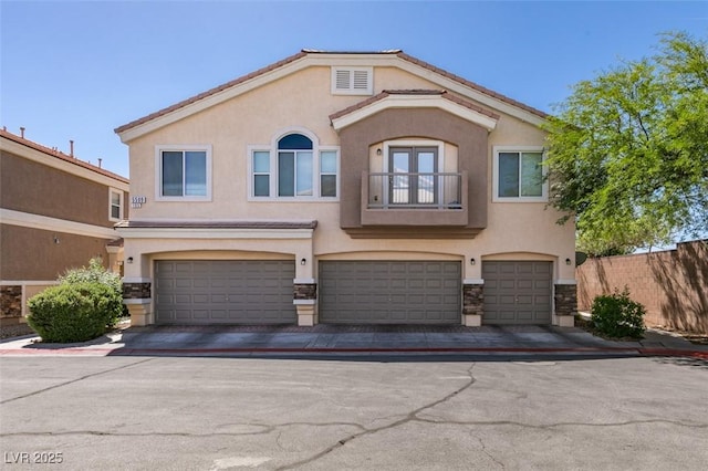 5509 Ante Up Ct Unit 102, Las Vegas, NV 89122 - view of front of house featuring a balcony, a garage, stucco siding, stone siding, and driveway