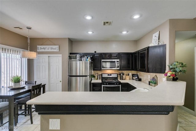 5509 Ante Up Ct Unit 102, Las Vegas, NV 89122 - kitchen featuring stainless steel appliances, dark cabinetry, light tile patterned flooring, light countertops, and tasteful backsplash